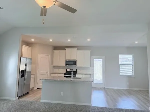 a view of kitchen with stainless steel appliances refrigerator stove microwave and cabinets