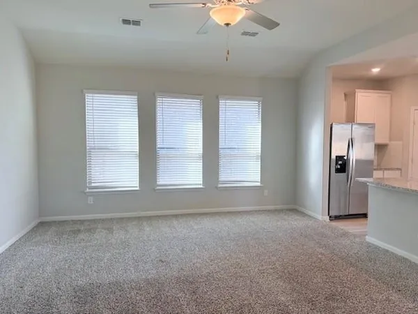 an empty room with chandelier fan and windows