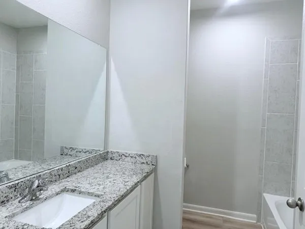 a bathroom with a granite countertop sink and a mirror
