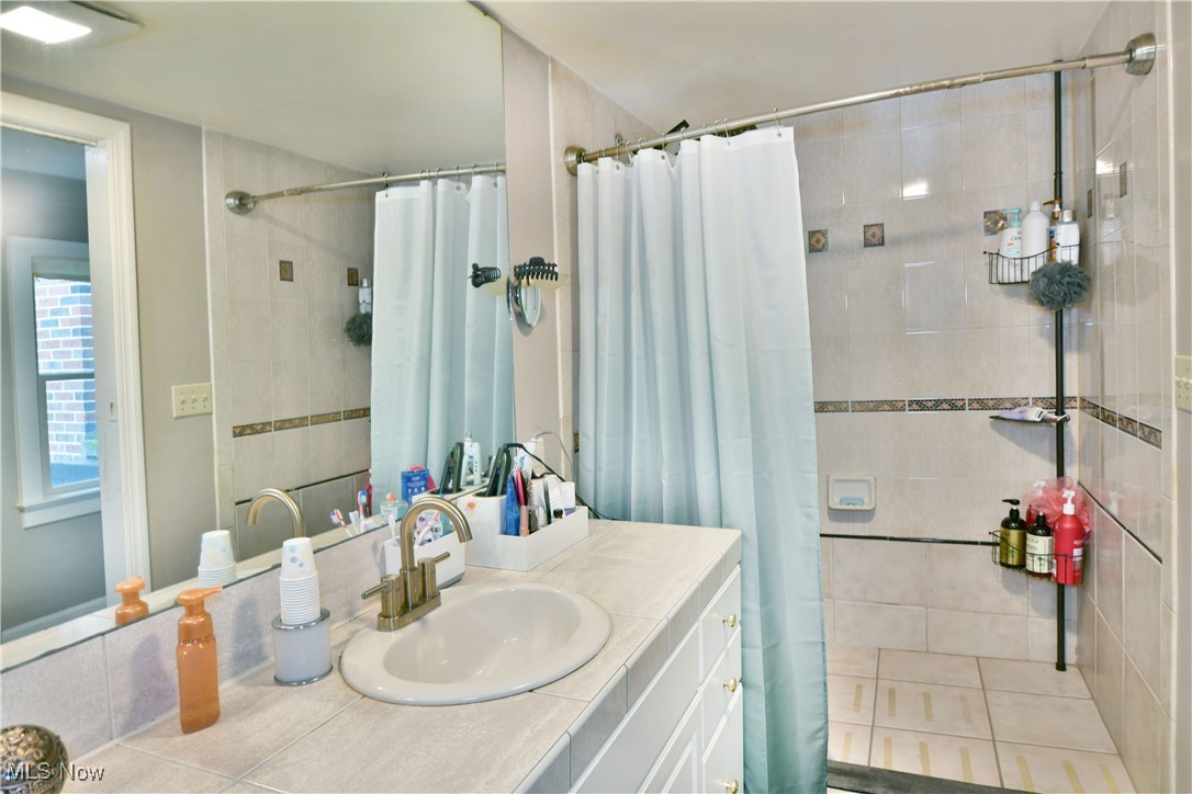 519 Butler Road Northeast Warren, OH 44483 - Photo 35 of 50 Bathroom featuring vanity, curtained shower, and tile patterned floors