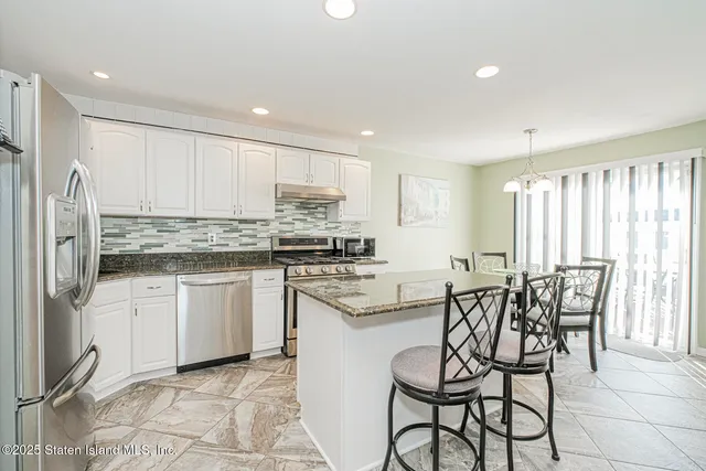 a kitchen with kitchen island granite countertop wooden cabinets and stainless steel appliances
