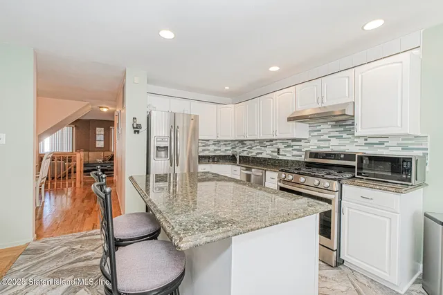 a kitchen with stainless steel appliances granite countertop a stove top oven a sink refrigerator and cabinets