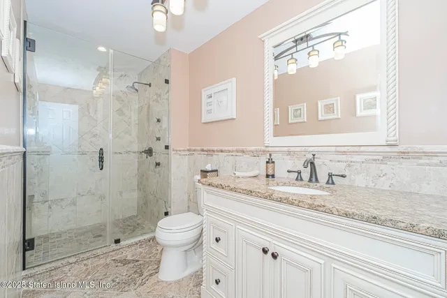 a bathroom with a granite countertop sink a toilet and shower