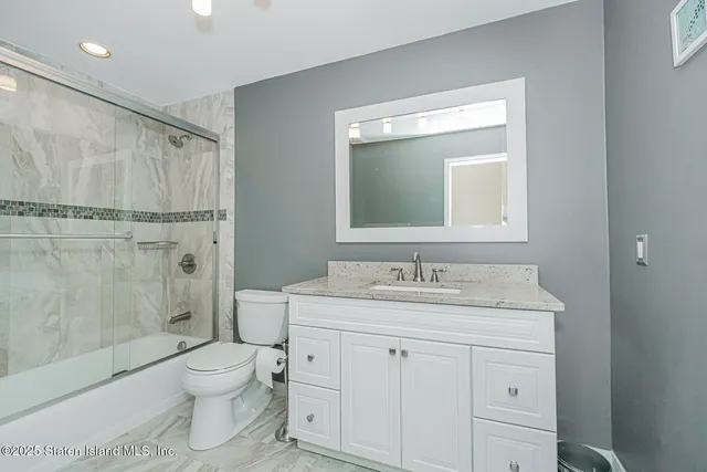 a bathroom with a granite countertop sink toilet a mirror a vanity and shower
