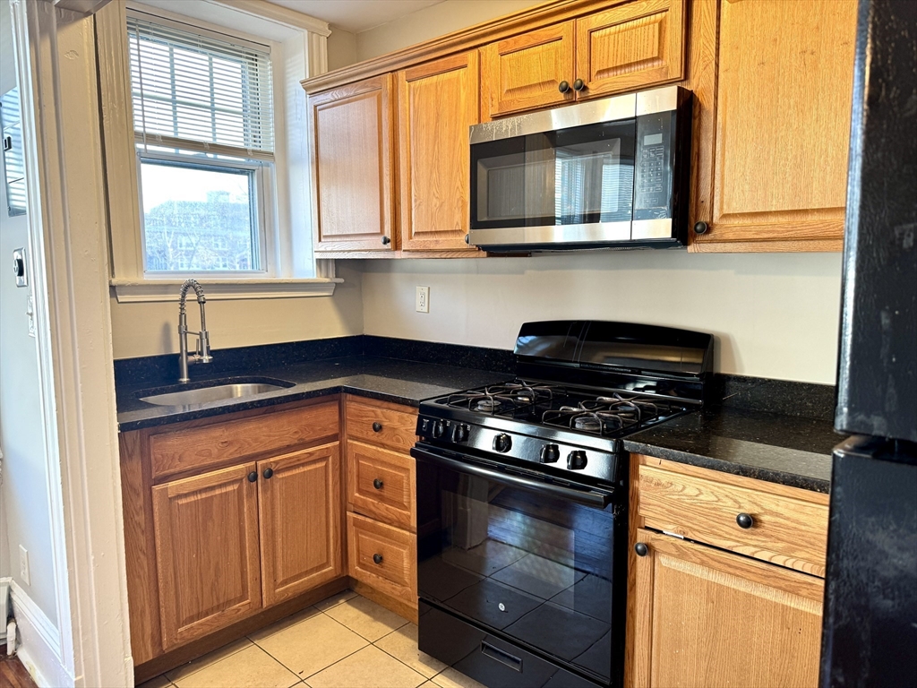 124 Green Street, Unit 206 Lynn, MA 01902 - Photo 2 of 7 a kitchen with stainless steel appliances granite countertop white cabinets and black stove top oven