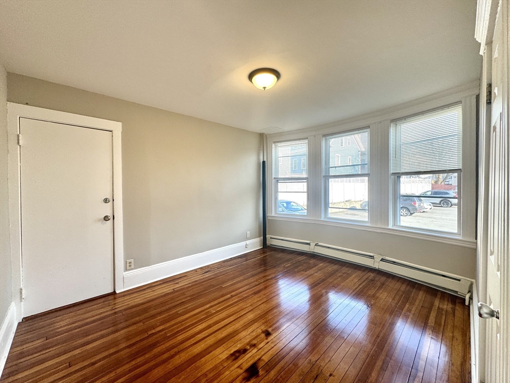 124 Green Street, Unit 206 Lynn, MA 01902 - Photo 6 of 7 a view of an empty room with wooden floor and a window