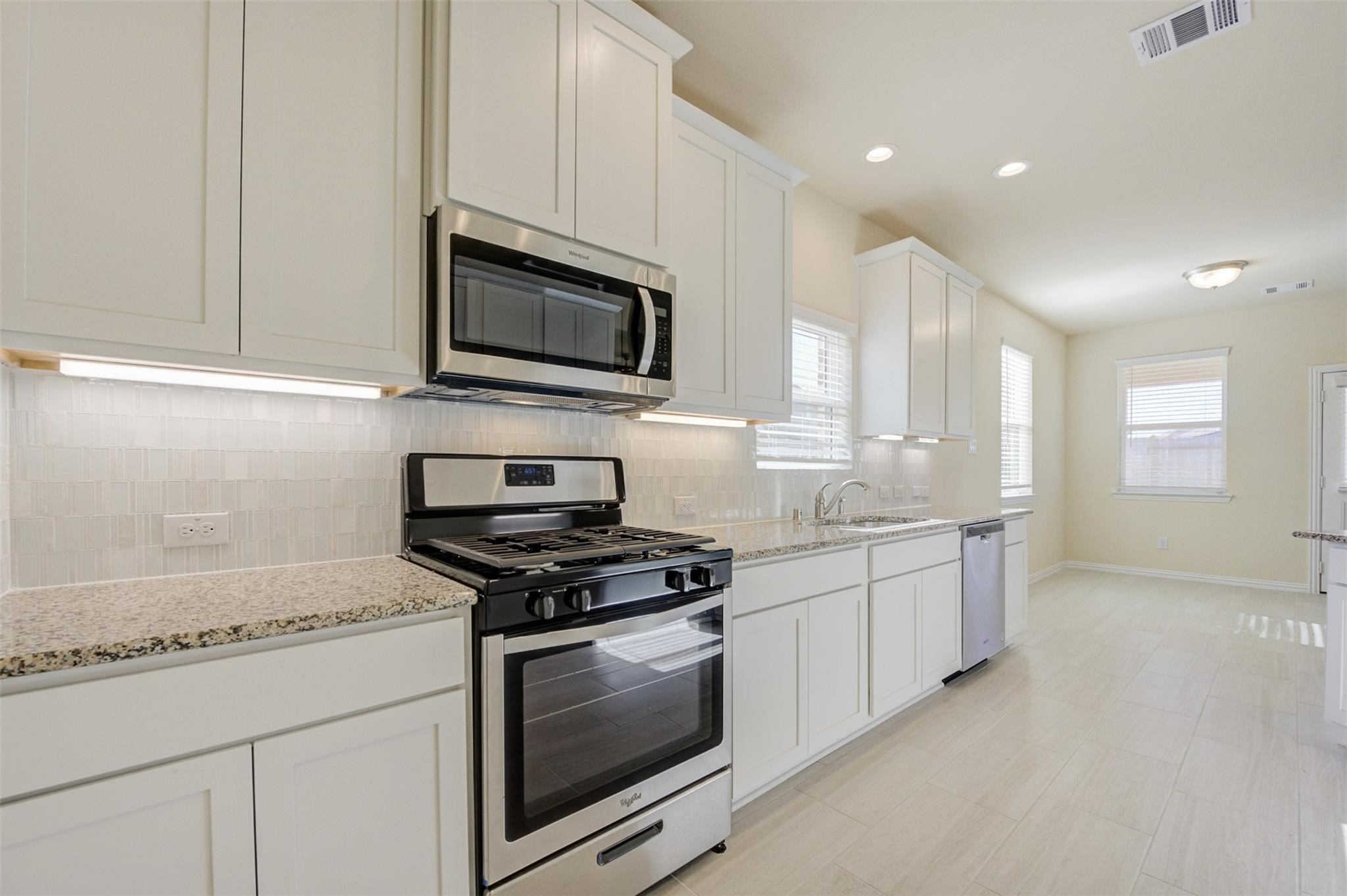 10902 Granite Chief Drive Rosharon, TX 77583 - Photo 10 of 32 a kitchen with stainless steel appliances granite countertop white cabinets granite counter tops and a hard wood floors