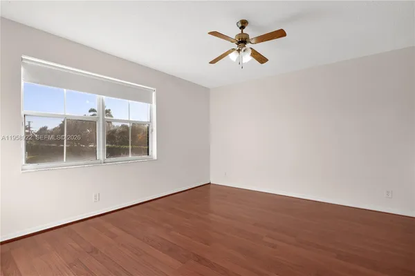 a view of a room with wooden floor and a ceiling fan