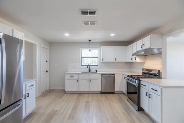 a large kitchen with stainless steel appliances granite countertop a stove a sink dishwasher and a refrigerator