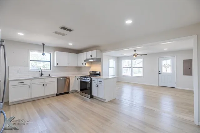 a large kitchen with a wooden floor and stainless steel appliances