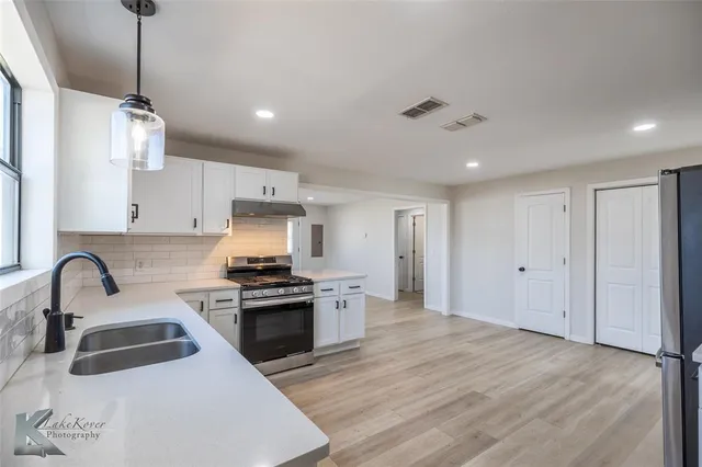 a kitchen with granite countertop a sink stainless steel appliances and cabinets