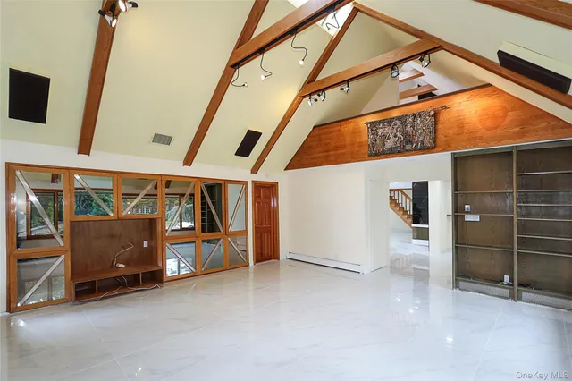 a view of an empty room with wooden floor and windows