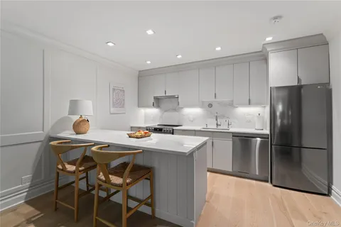 a kitchen with stainless steel appliances granite countertop a dining table chairs refrigerator and sink
