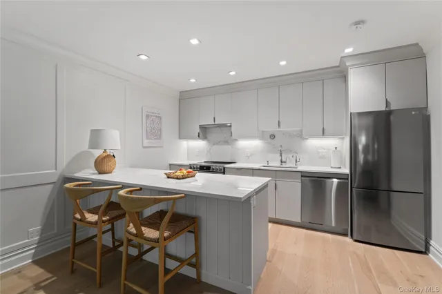 a kitchen with stainless steel appliances granite countertop a dining table chairs refrigerator and sink