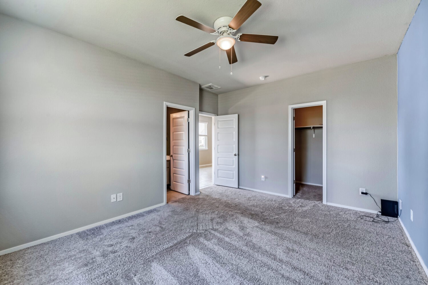 1310 Goforth Road Kyle, TX 78640 - Photo 15 of 24 Spacious room featuring light gray wall paint, textured carpeting, and a ceiling fan with integrated lighting