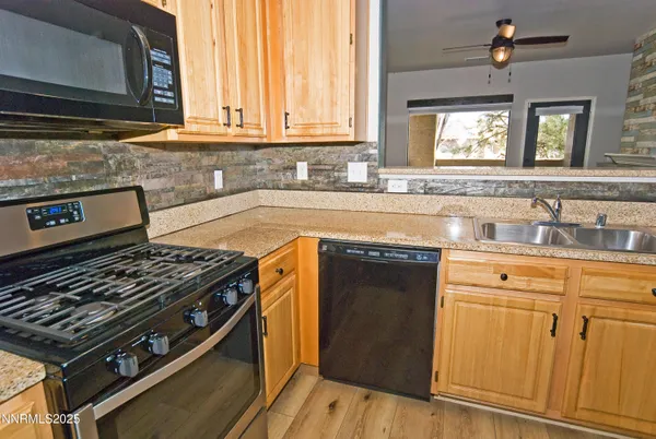 a kitchen with granite countertop a stove a sink and dishwasher wooden cabinets with granite countertops