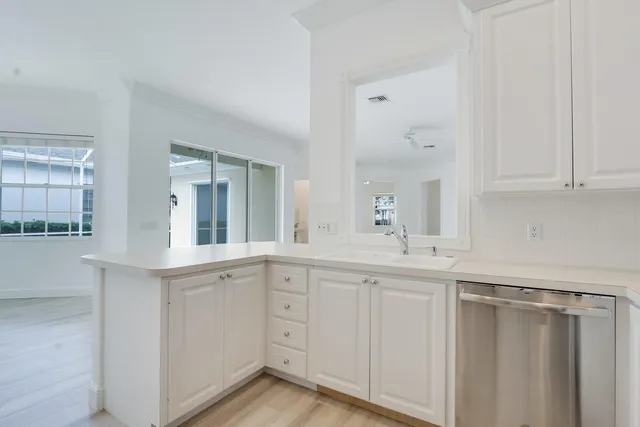 a kitchen with white cabinets and sink