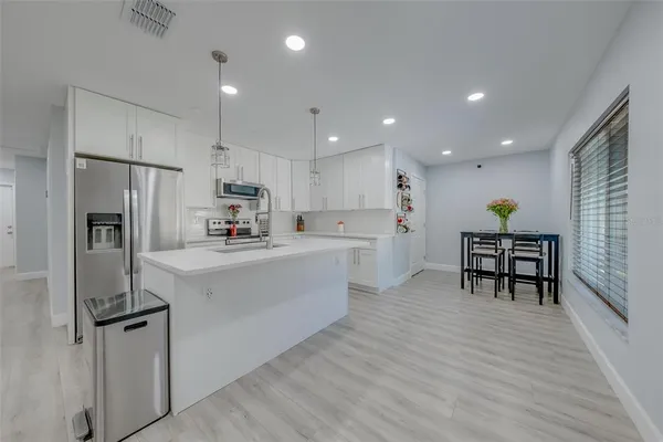 a kitchen with stainless steel appliances a refrigerator and a stove top oven with wooden floor