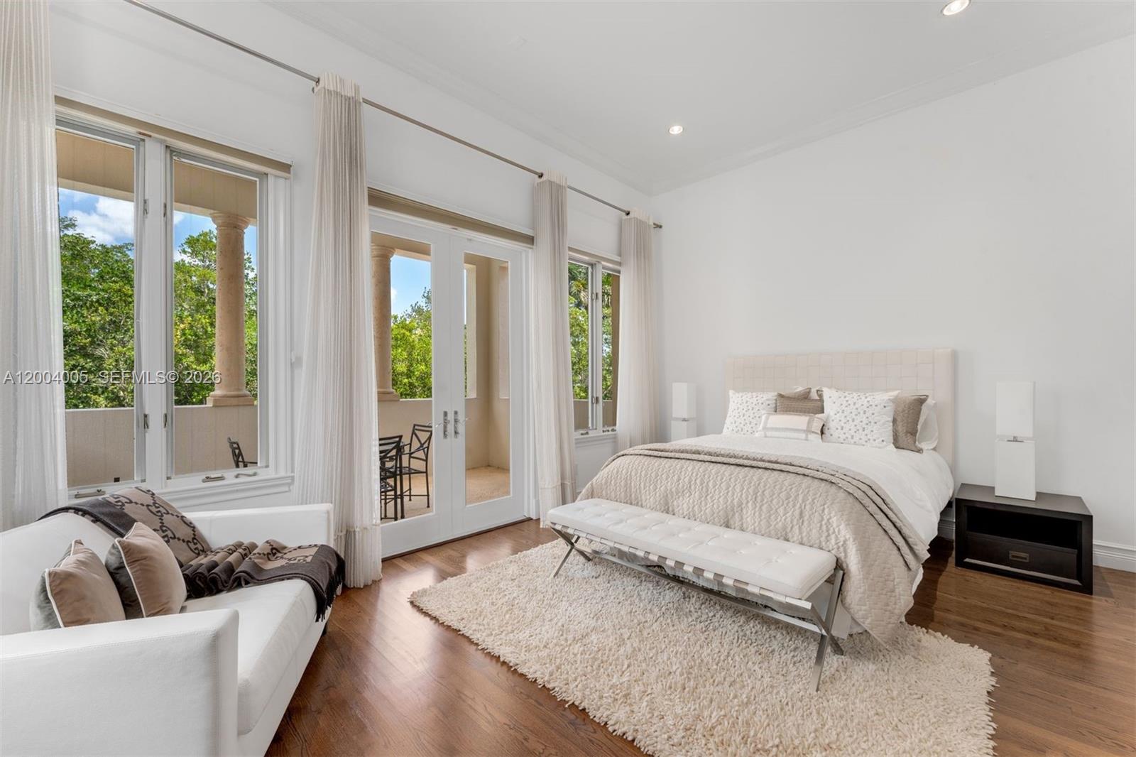 255 Cocoplum Road Coral Gables, FL 33143 - Photo 22 of 29 a spacious bedroom with a bed and a couch with large window