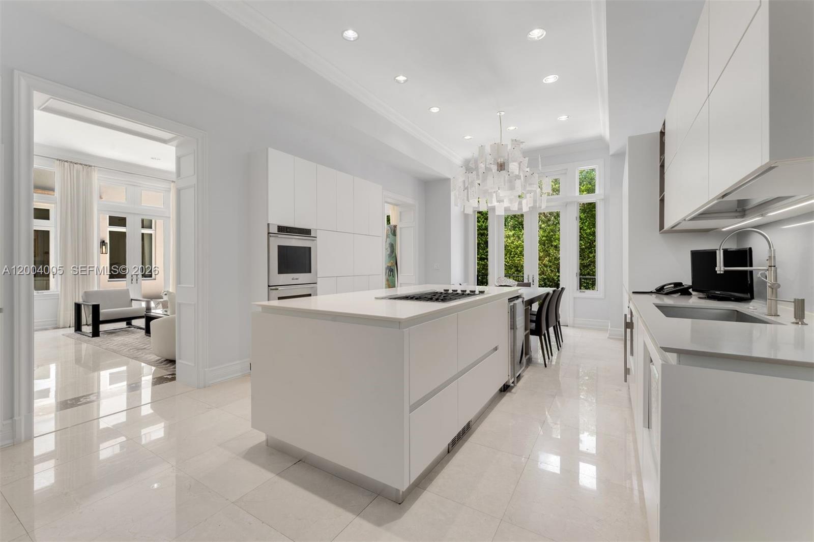 255 Cocoplum Road Coral Gables, FL 33143 - Photo 8 of 29 a large white kitchen with stainless steel appliances kitchen island a large counter top and a stove