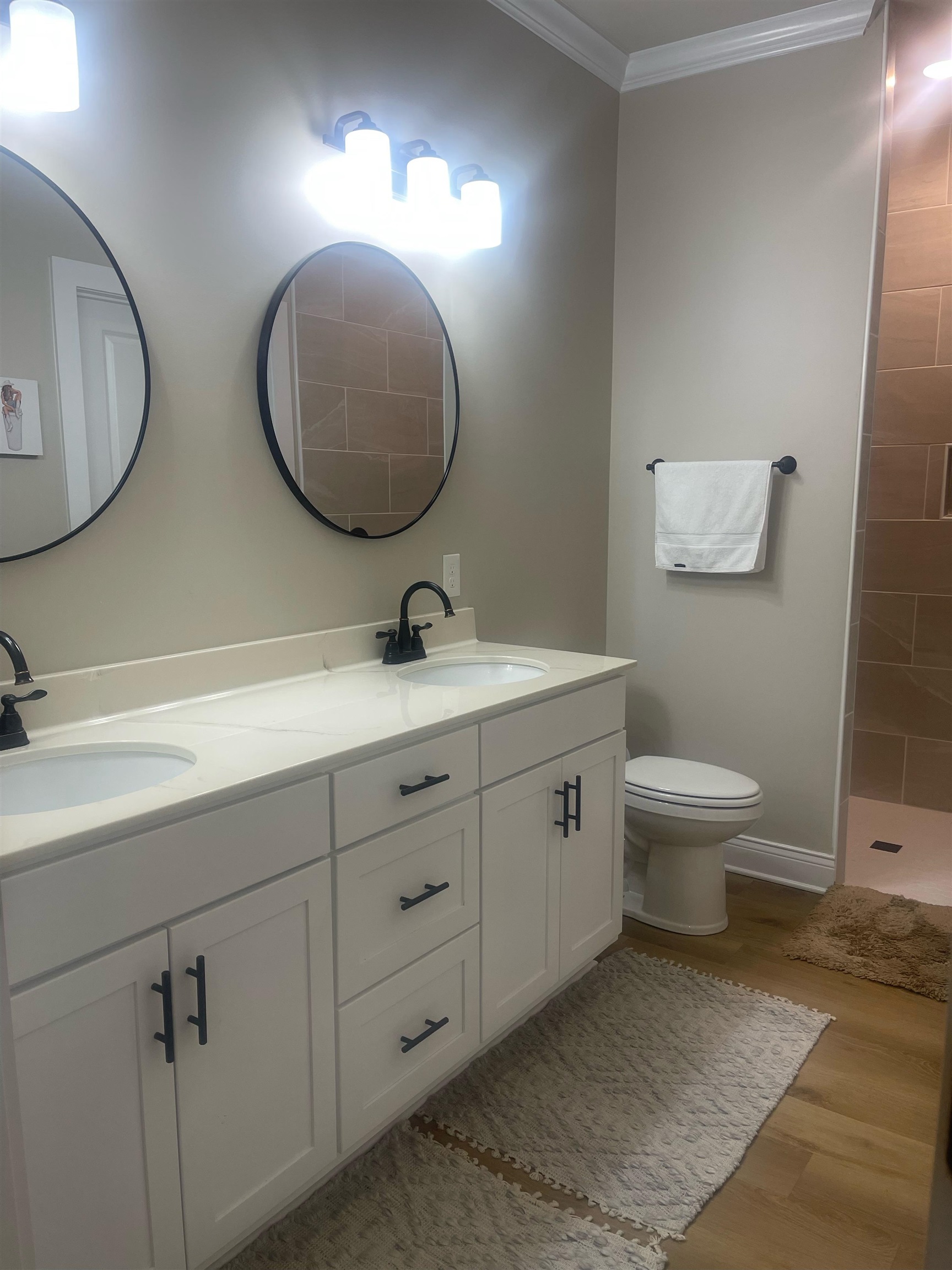 210 Church Street Ripley, TN 38063 - Photo 14 of 21 Double vanity with white cabinetry and black hardware, stone countertop, two undermount sinks, and two round black-framed mirrors