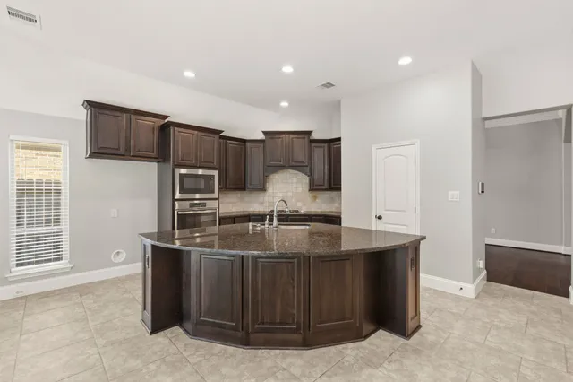 a kitchen with kitchen island granite countertop a sink and a refrigerator