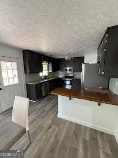 a living room with stainless steel appliances kitchen island granite countertop a sink and a wooden floors