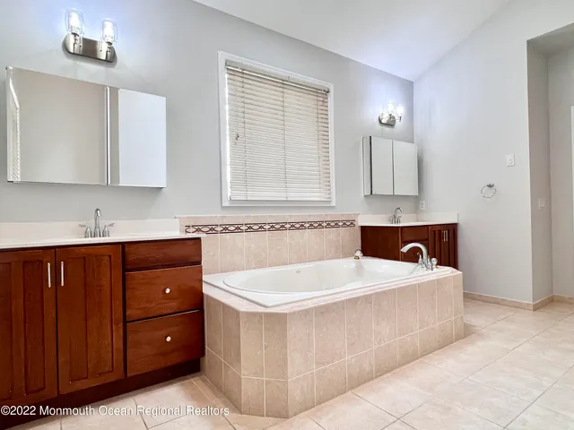 a bathroom with a tub a sink a mirror and a bathtub