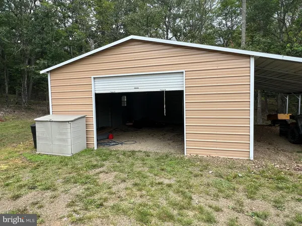 a view of a white house with a small yard and a large parking space
