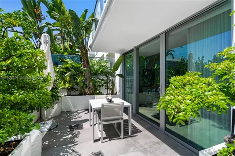 a view of a patio with table and chairs potted plants and floor to ceiling window