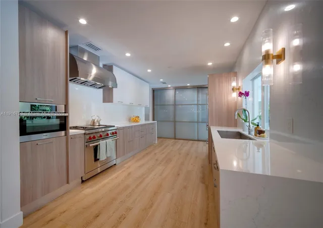 a kitchen with stainless steel appliances granite countertop a sink a stove and a wooden floors