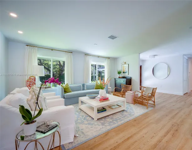a living room with furniture couches and a dining table with wooden floor