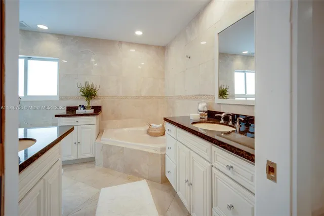 a bathroom with a sink a bathtub a mirror a vanity and a shower