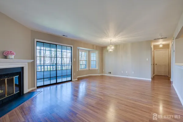 a view of an empty room with wooden floor fireplace and a window