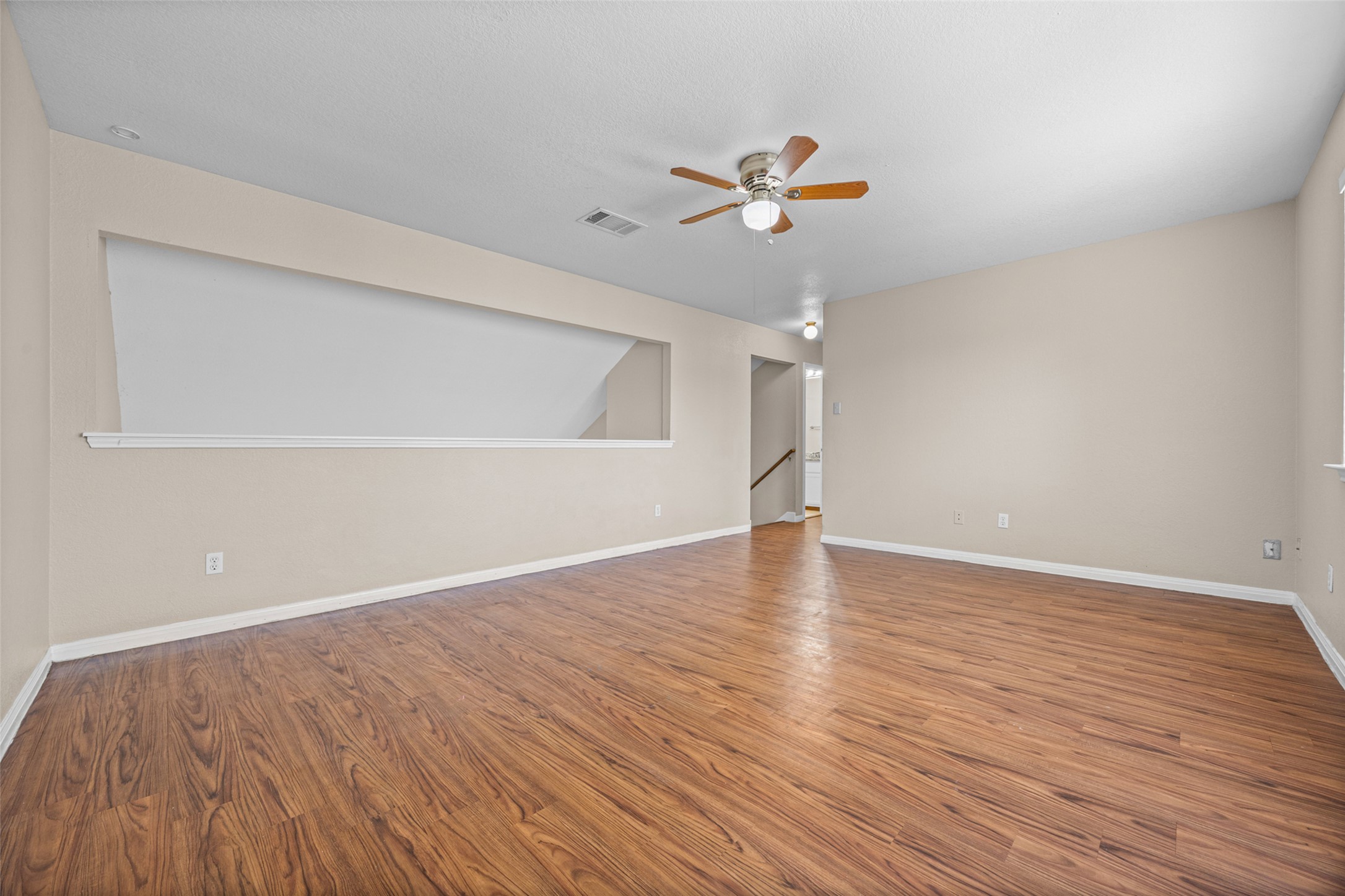 2432 Roundabout Lane Round Rock, TX 78664 - Photo 17 of 22 A spacious living area featuring rich hardwood flooring and a functional ceiling fan for optimal comfort.