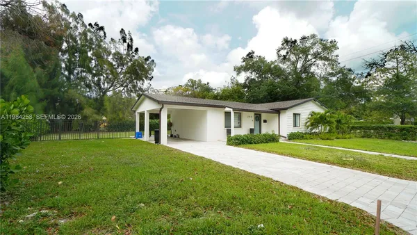 a front view of a house with a yard and trees
