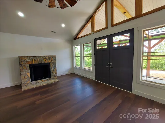 an empty room with wooden floor fireplace and windows