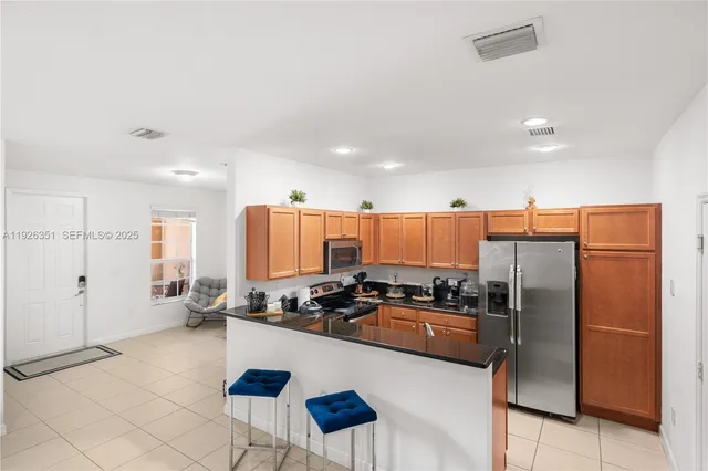 a kitchen with stainless steel appliances granite countertop a refrigerator a stove a sink a dining table and chairs