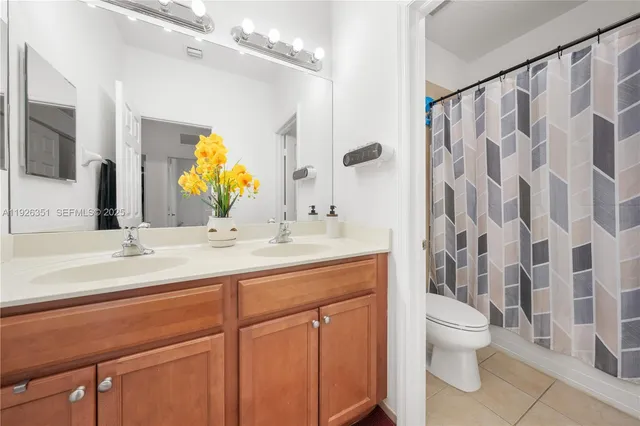 a bathroom with a double vanity sink toilet mirror and shower