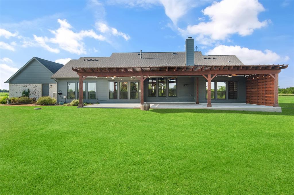 1019 Vaughan Lane Tioga, TX 76271 - Photo 40 of 40 Expansive green lawn with a covered patio featuring a wood pergola and a privacy screen