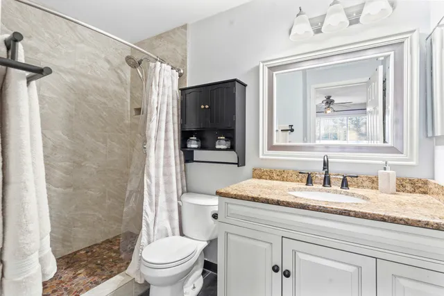 a bathroom with a granite countertop sink toilet and shower