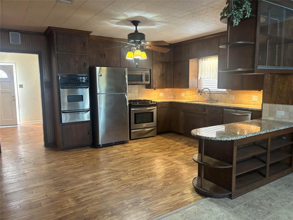 1103 West 11th Street McGregor, TX 76657 - Photo 2 of 15 a kitchen with stainless steel appliances granite countertop a sink counter space and wooden floor