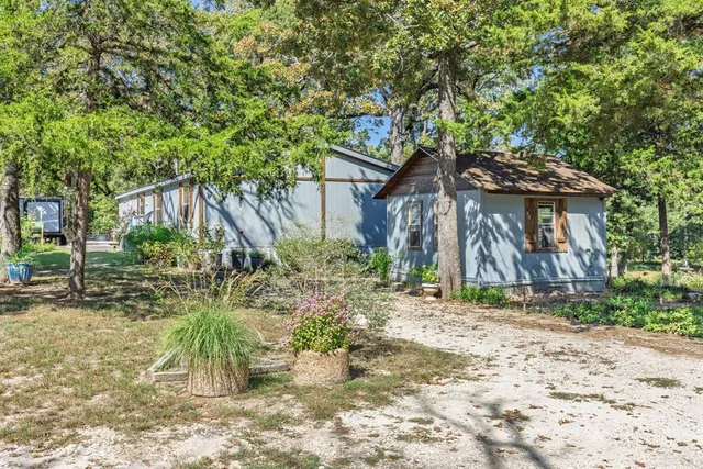 a backyard of a house with table and chairs under an umbrella