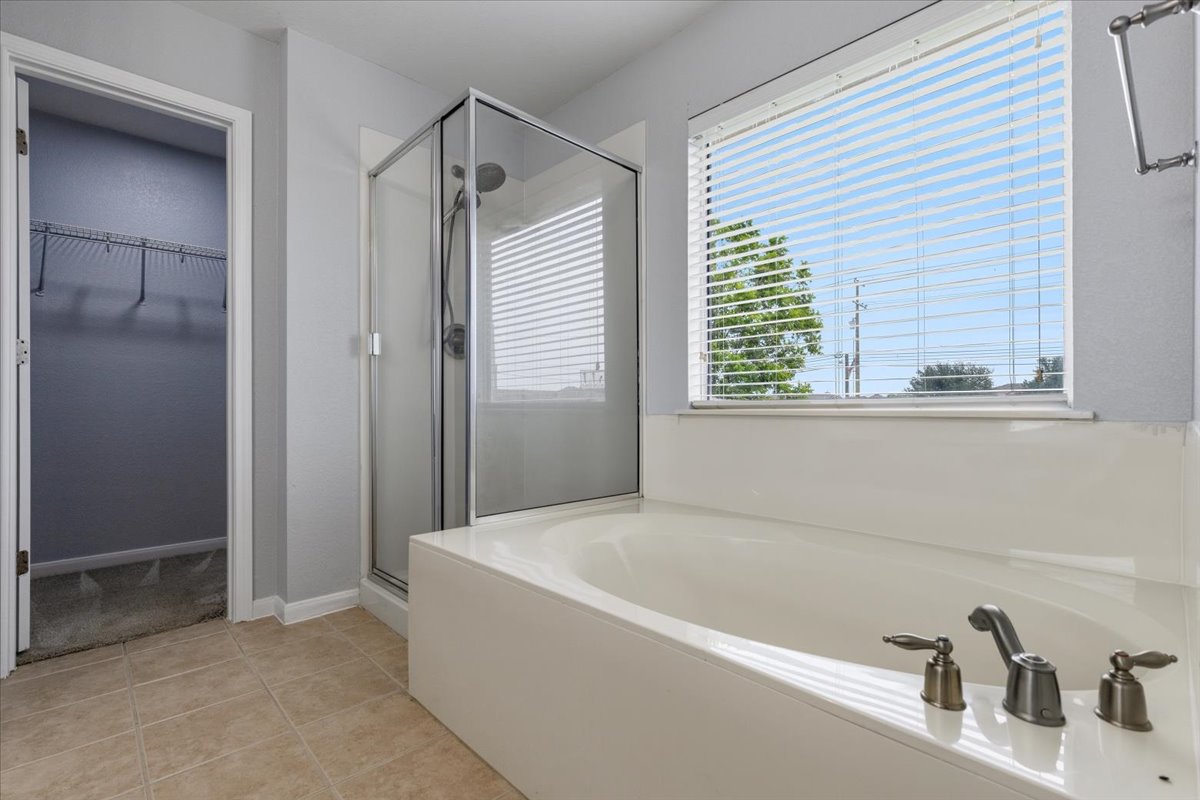 17812 Masi Loop Pflugerville, TX 78660 - Photo 23 of 38 Deep soaking tub with bronze-finish fixtures, adjacent to a glass-enclosed shower