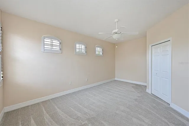 an empty room with windows and ceiling fan