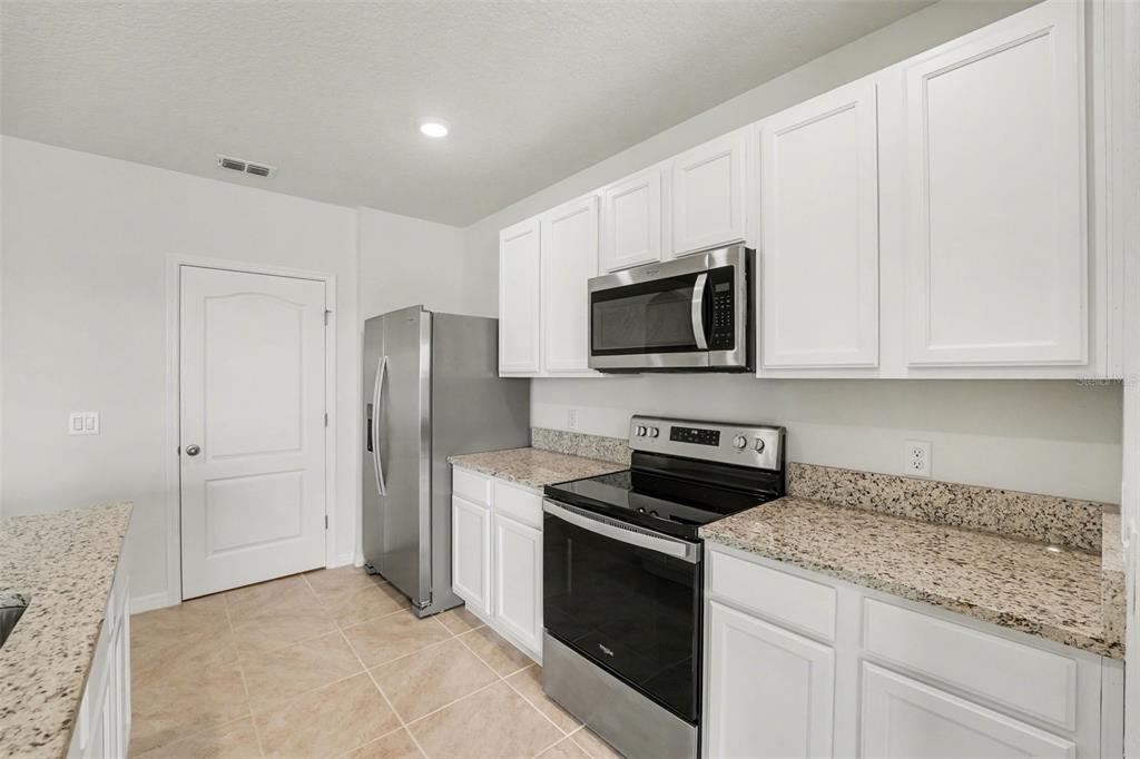 2795 Grandbury Grove Road Lakeland, FL 33811 - Photo 11 of 35 a kitchen with stainless steel appliances granite countertop white cabinets and refrigerator