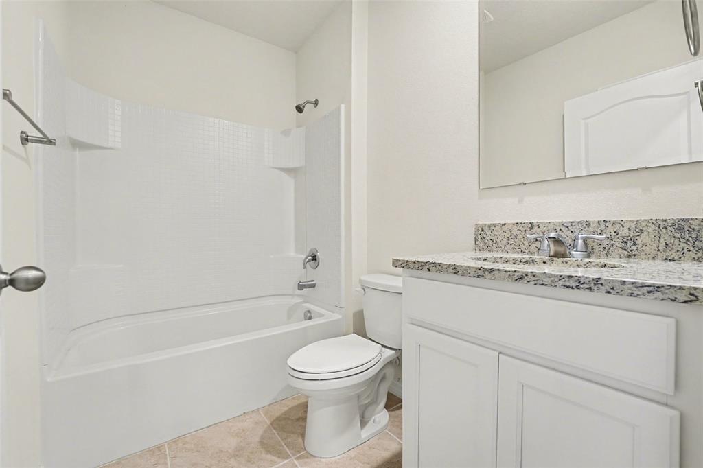 2795 Grandbury Grove Road Lakeland, FL 33811 - Photo 22 of 35 a bathroom with a granite countertop toilet a sink and bathtub