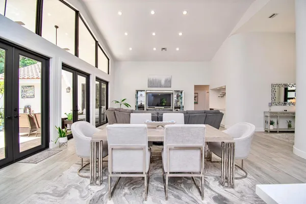 a kitchen with stainless steel appliances a refrigerator a sink a stove and white cabinets with wooden floor