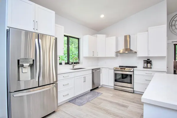 a kitchen with stainless steel appliances granite countertop a stove a sink and a refrigerator