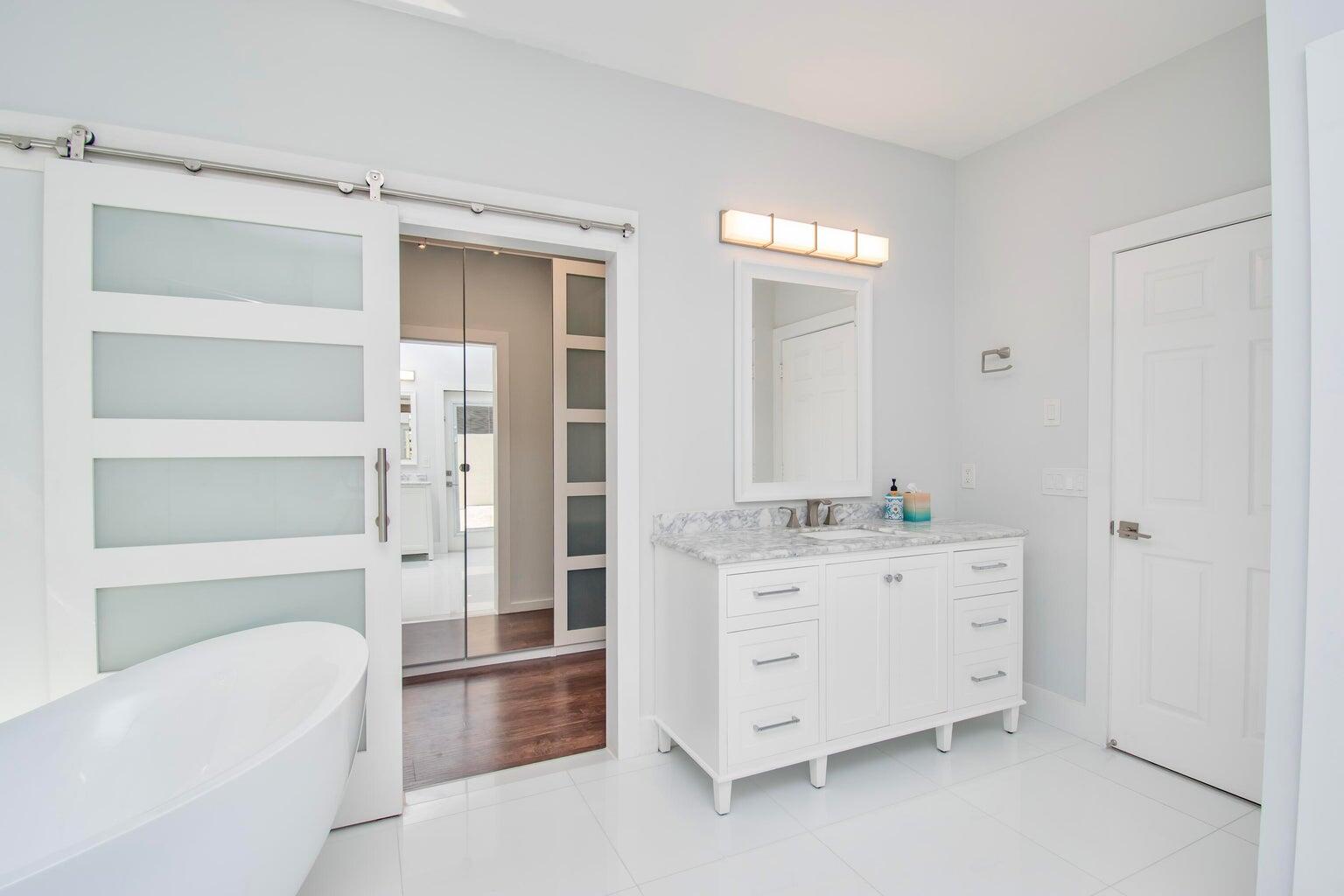 2302 Northwest 66th Drive Boca Raton, FL 33496 - Photo 33 of 53 a bathroom with a double vanity sink a mirror and a bathtub